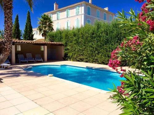 a swimming pool in front of a house with flowers at Domaine de l'Aufrene in Hyères