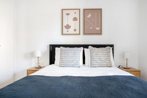 a bedroom with a bed with a blue blanket and two lamps at Blueground Dreta de lEixample nr pl catalunya BCN-42 in Barcelona