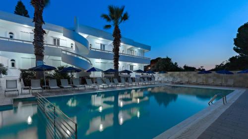 a hotel with a swimming pool in front of a building at Paleos Hotel Apartments in Ialyssos