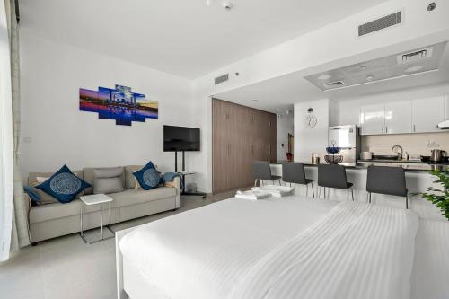 Silkhaus Luxury studio in Saadiyat Island في أبوظبي: غرفة معيشة بيضاء مع أريكة ومطبخ
