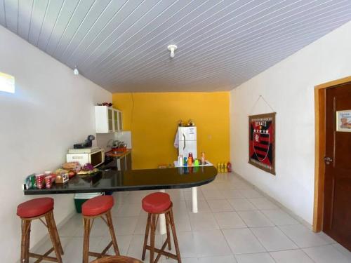 a kitchen with a counter and stools in a room at Chalé de Praia - Salinopolis/Pa in Salinópolis