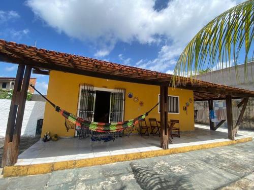 a yellow house with a hammock in front of it at Chalé de Praia - Salinopolis/Pa in Salinópolis