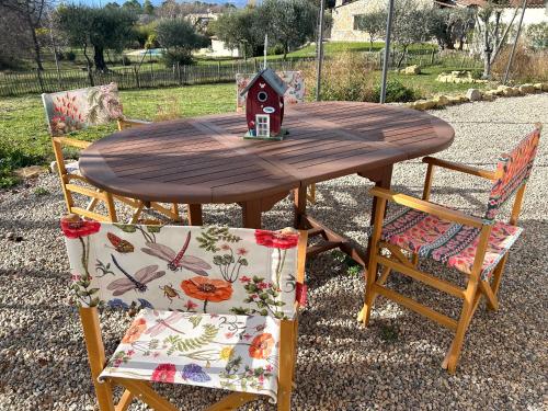 a wooden table with two chairs and a bird house on it at Maison à la campagne 4 personnes in Montauroux