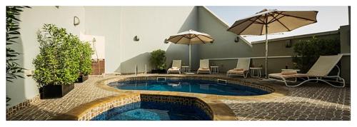 a swimming pool with umbrellas in a courtyard at Executive Suites Abu Dhabi in Abu Dhabi