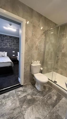a bathroom with a toilet and a shower and a bed at Charlotte Guest House in London