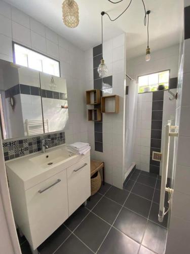 a white bathroom with a sink and a shower at La terrasse Majorelle. in Le Passage