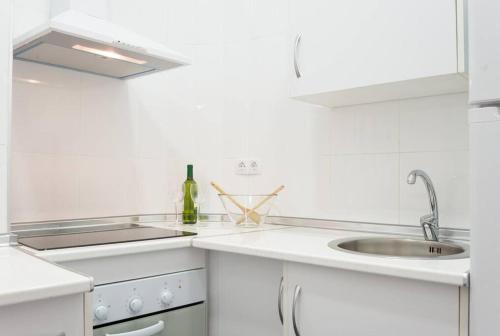 マラガにあるSunny Málaga Apartmentsの白いキッチン(シンク、ワイン1本付)