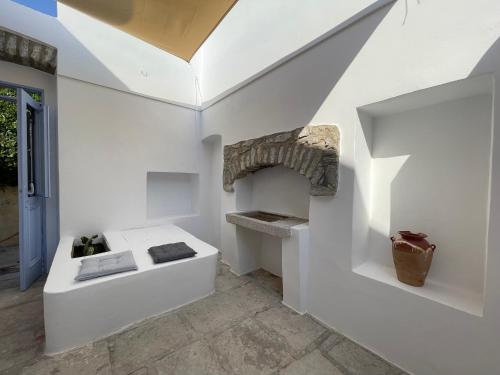 Habitación con pared blanca y chimenea de piedra. en Anamar Symi Residences, en Symi