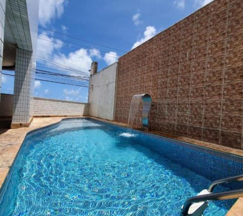 una piscina frente a un edificio de ladrillo en PONTA NEGRA FLAT, en Natal