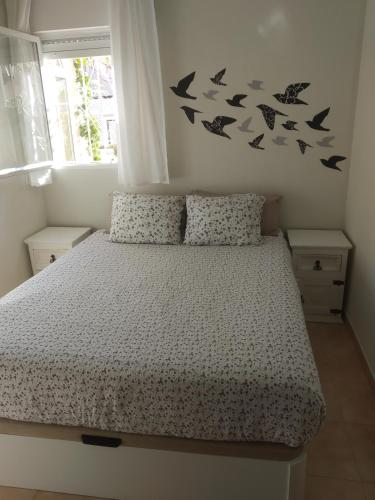 a bedroom with a bed with birds on the wall at CASA GORRIÓN in Los Alcázares