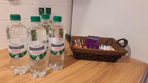 three bottles of water and a basket on a table at Barwny Zakątek in Augustów