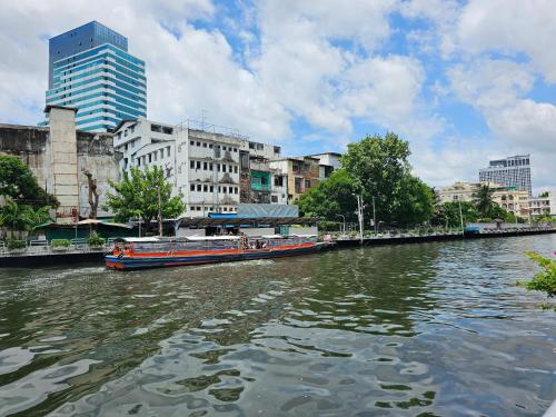 a boat traveling down a river in a city at 206HiddenNest, Local Room with Street Food only 15 min walk to Skytrain in Bangkok