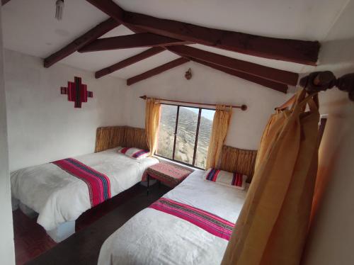 a bedroom with two twin beds and a window at INTI WASI LODGE in Comunidad Yumani