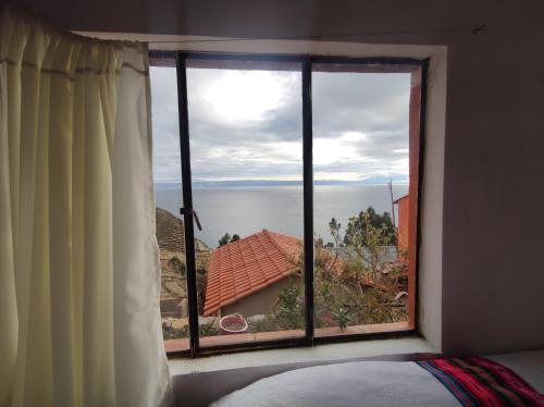 a bedroom window with a view of the water at INTI WASI LODGE in Comunidad Yumani