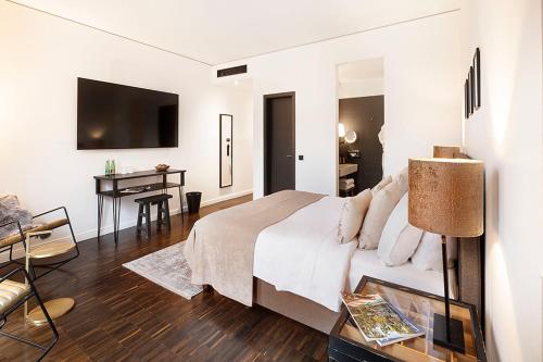 a white bedroom with a bed and a desk at The Weinmeister Berlin-Mitte - Adults Only in Berlin