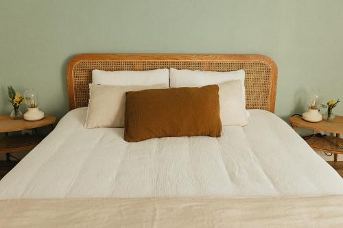 a bed with a brown pillow on it with two tables at Mercerie de Denise in Le Bourg-Dun