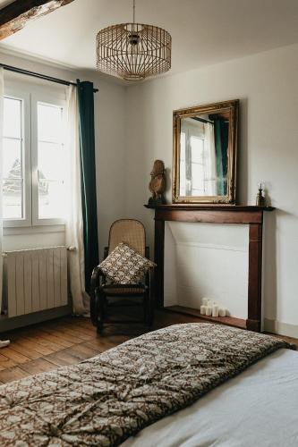 a bedroom with a bed and a mirror and a chair at Mercerie de Denise in Le Bourg-Dun