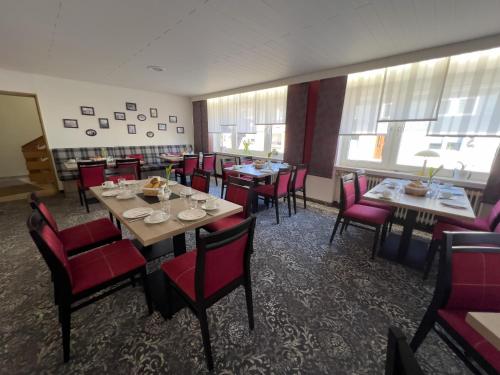 a dining room with tables and red chairs at Hotel Haus Christel in Willingen