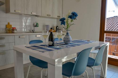a kitchen with a table with wine glasses and blue chairs at Blue Lagoon Home in Sulzano