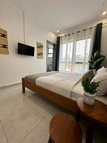 a bedroom with a large bed and a television at Coalescence Hotel Rwanda in Kigali