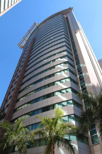 ein hohes Gebäude mit Palmen davor in der Unterkunft Quarto de hotel entre os Shoppings Vila Olimpia e JK Iguatemi in São Paulo