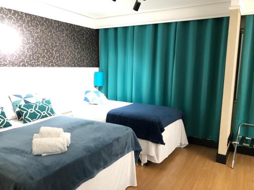 two beds in a room with green curtains at Quarto de hotel entre os Shoppings Vila Olimpia e JK Iguatemi in Sao Paulo