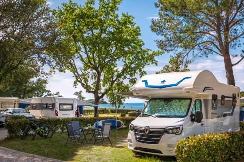 a white truck parked in a campsite with a table and chairs at Maistra Camping Valkanela Pitches in Funtana