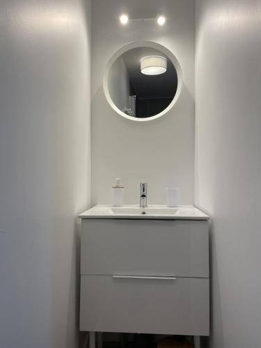une salle de bain blanche avec un lavabo et un miroir dans l'établissement Appartement proche mer, à Aytré