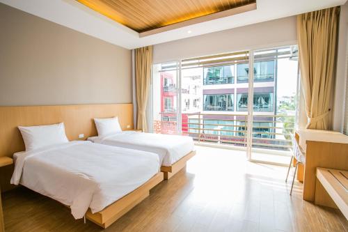 1 dormitorio con 2 camas y ventana grande en Casa de Coral Boutique Hotel, en Kata Beach