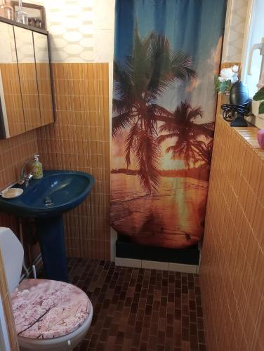 Łazienka wyposażona jest w umywalkę i zasłonę prysznicową z palmami. w obiekcie Studio Marie w mieście Belbeuf