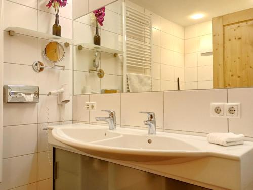 uma casa de banho branca com um lavatório e um espelho em Drei Türme 2 em Schruns