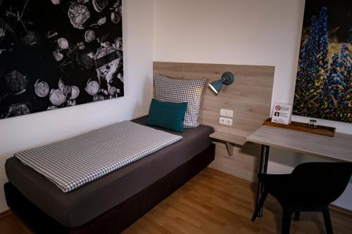 Habitación pequeña con cama y escritorio. en Stadtplatz23 B&B en Bogen