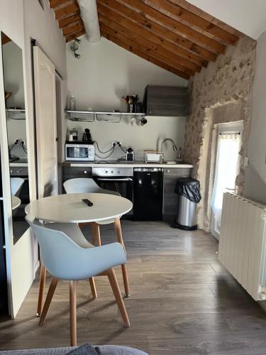 une petite cuisine avec une table blanche et une chaise dans l'établissement Petit studio Le Pigeonnier à 5 mn de Lourmarin, à Puyvert