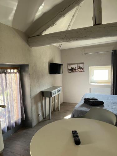 een kamer met een bed en een tafel met afstandsbediening bij Petit studio Le Pigeonnier à 5 mn de Lourmarin in Puyvert