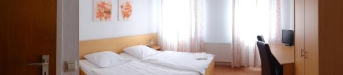 a bedroom with a bed with white sheets and pillows at Hotel-Restaurant Zum Goldenen Hahnen in Markgröningen