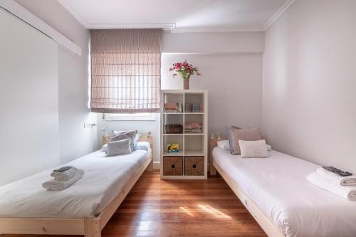 two beds in a room with white walls and wooden floors at Arkotxa apartment by People Rentals in Getxo