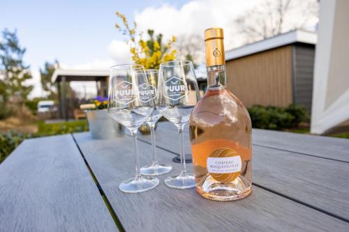 una bottiglia di vino seduta su un tavolo con bicchieri da vino di Familiepark TOP Vredeoord a Voorthuizen