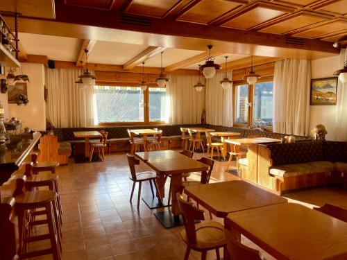 a restaurant with tables and chairs and a bar at Hotel Oasi in San Vito di Cadore