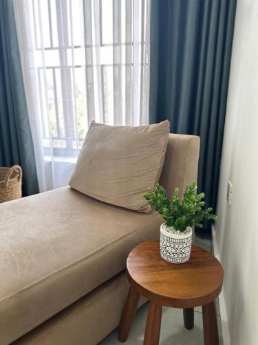 a couch with a pillow and a table with a plant at Coalescence Hotel Rwanda in Kigali