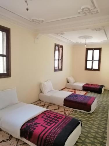 a room with two beds and a couch in it at Gite chez Ali Agouti Maison Berbère in Agouti