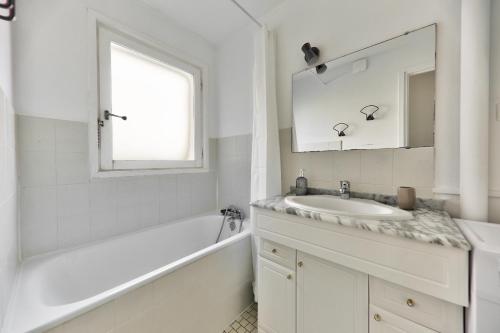 une salle de bain blanche avec un lavabo et un miroir dans l'établissement Belle terrasse avec vue sur l'océan - 90m de la plage, à Arzon