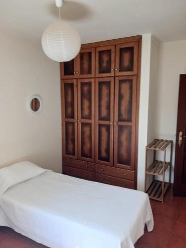 una camera da letto con un grande armadio in legno e un letto bianco di GBT Quartos a Sines