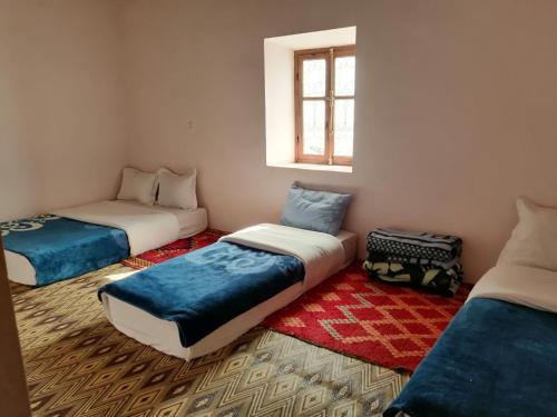 een kamer met 3 bedden en een raam bij Gite chez Ali Agouti Maison Berbère in Idoukaln