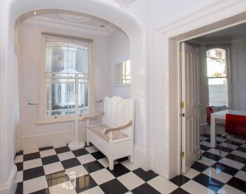a room with a chair and a checkerboard floor at Beautiful Victorian Coastal Holiday Home in Kent