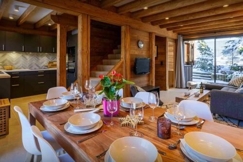 une table en bois avec des chaises blanches et une salle à manger dans l'établissement Chalet Kouzya - OVO Network, aux Gets