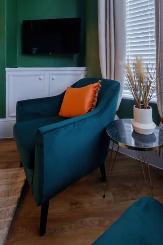 a blue couch with an orange pillow and a table at The Green House 3 Bed House - Contractors, Families, Close to city centre, Free Parking in Doncaster