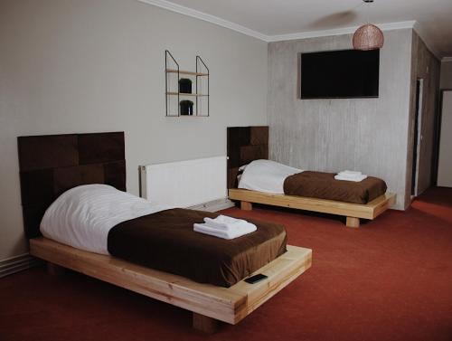 a bedroom with two beds and a flat screen tv at Popasul Graniceresc in Năsăud