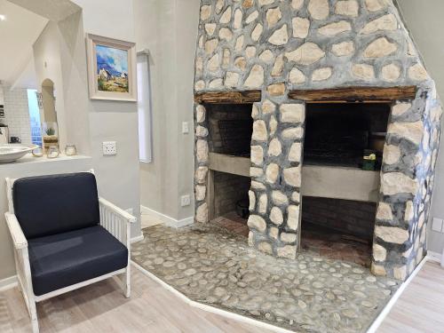 a stone fireplace in a living room with a chair at Engel in Struisbaai