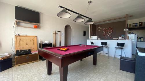 - une table de billard rouge dans une pièce avec cuisine dans l'établissement Le Panache, à Sevremont