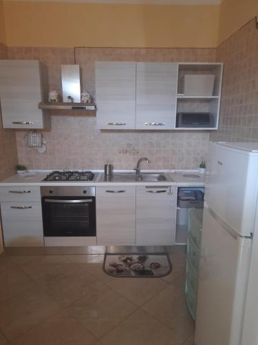 eine Küche mit weißen Schränken, einer Spüle und einem Kühlschrank in der Unterkunft Casa Lulù in Santa Maria La Carità